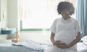 Pregnant African American woman holding her stomach in hospital