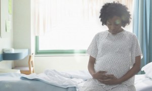 Pregnant African American woman holding her stomach in hospital