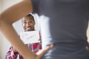 Man showing 'I'm Sorry' sign to angry girlfriend