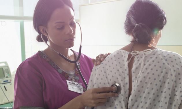 Nurse listening to heartbeat of patient in hospital room