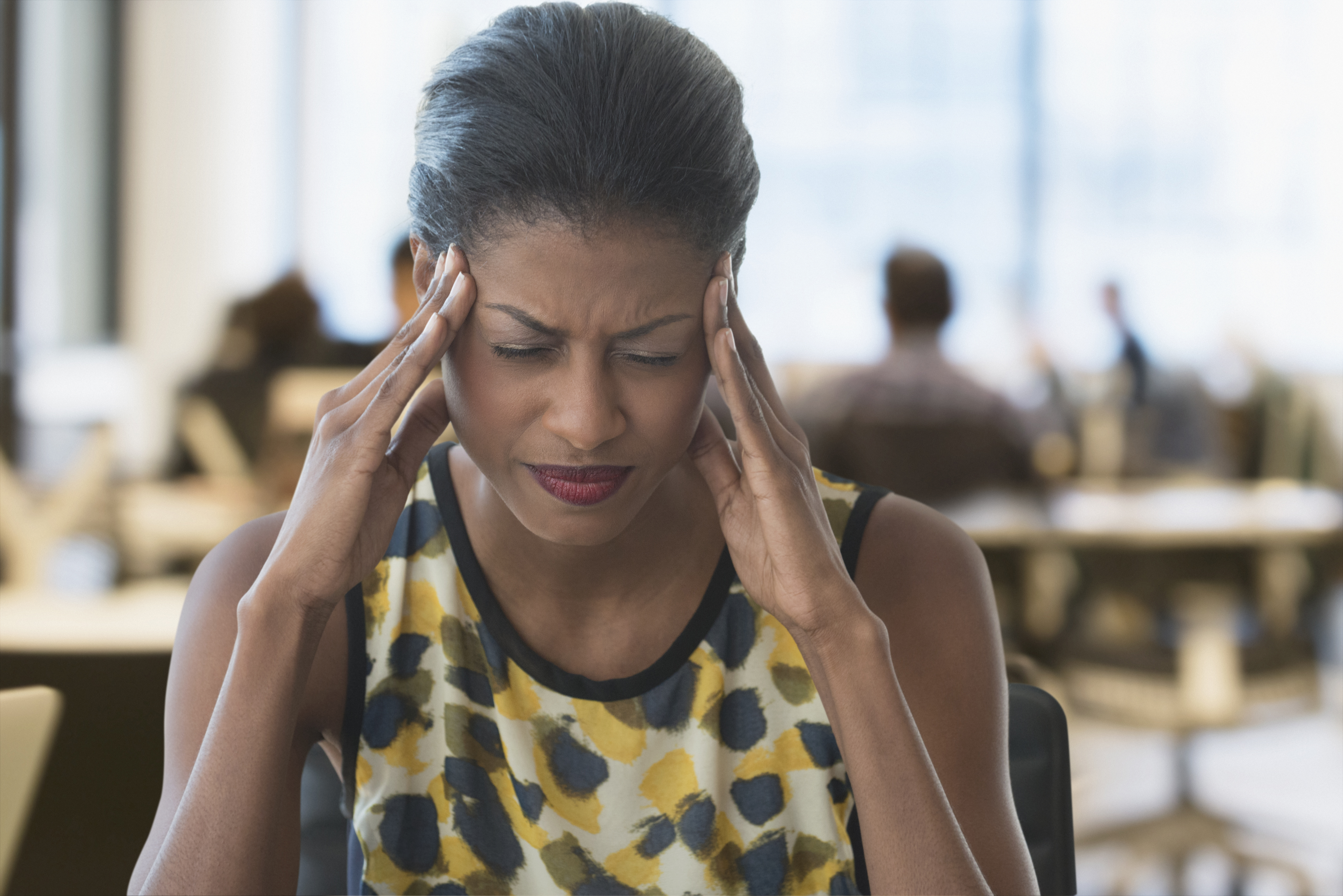 Anxious mixed race businesswoman rubbing temples in office