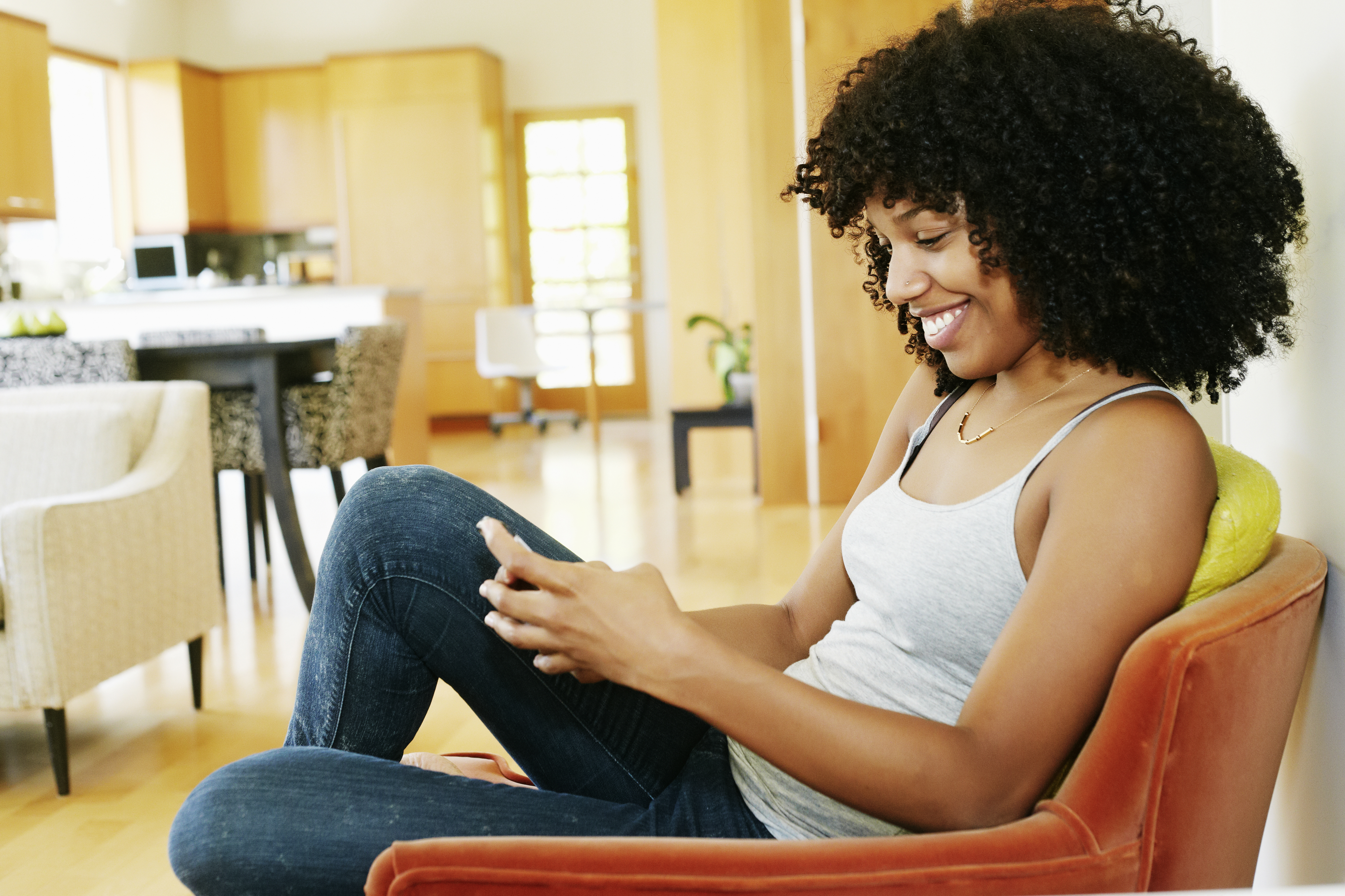 Mixed race woman using cell phone in armchair