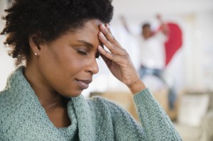 Black woman with headache and playful son in background