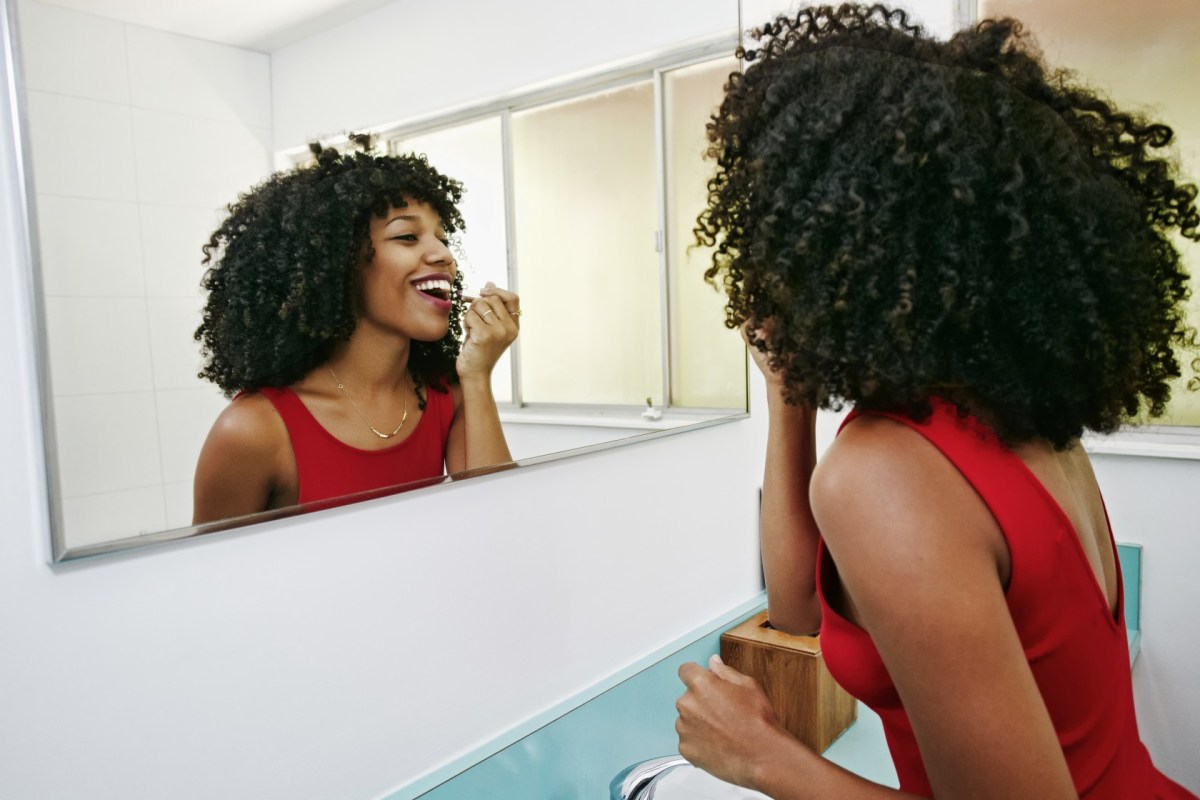 Mixed race woman applying makeup in mirror