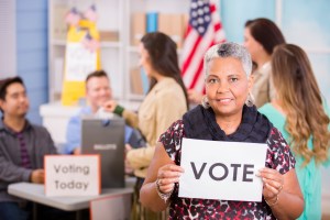 Voters register, voting in USA elections. Woman holds 'Vote' sign.