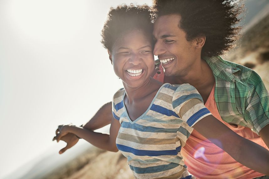 A couple with arms outstretched in a gesture of freedom and excitement, leaning into the breeze.