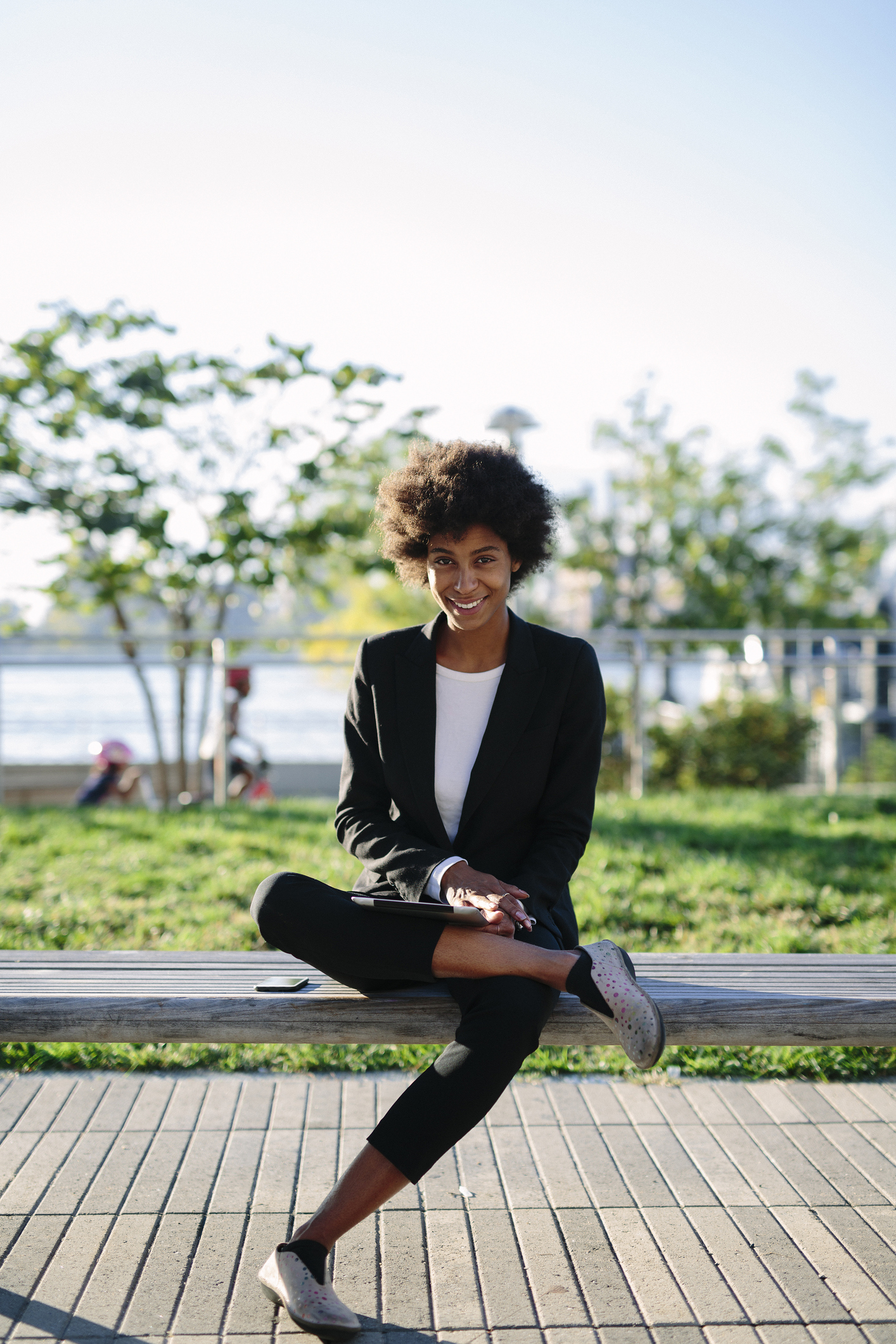 USA, New York City, portrait of smiling businesswoman sitting on a bench with digital tablet