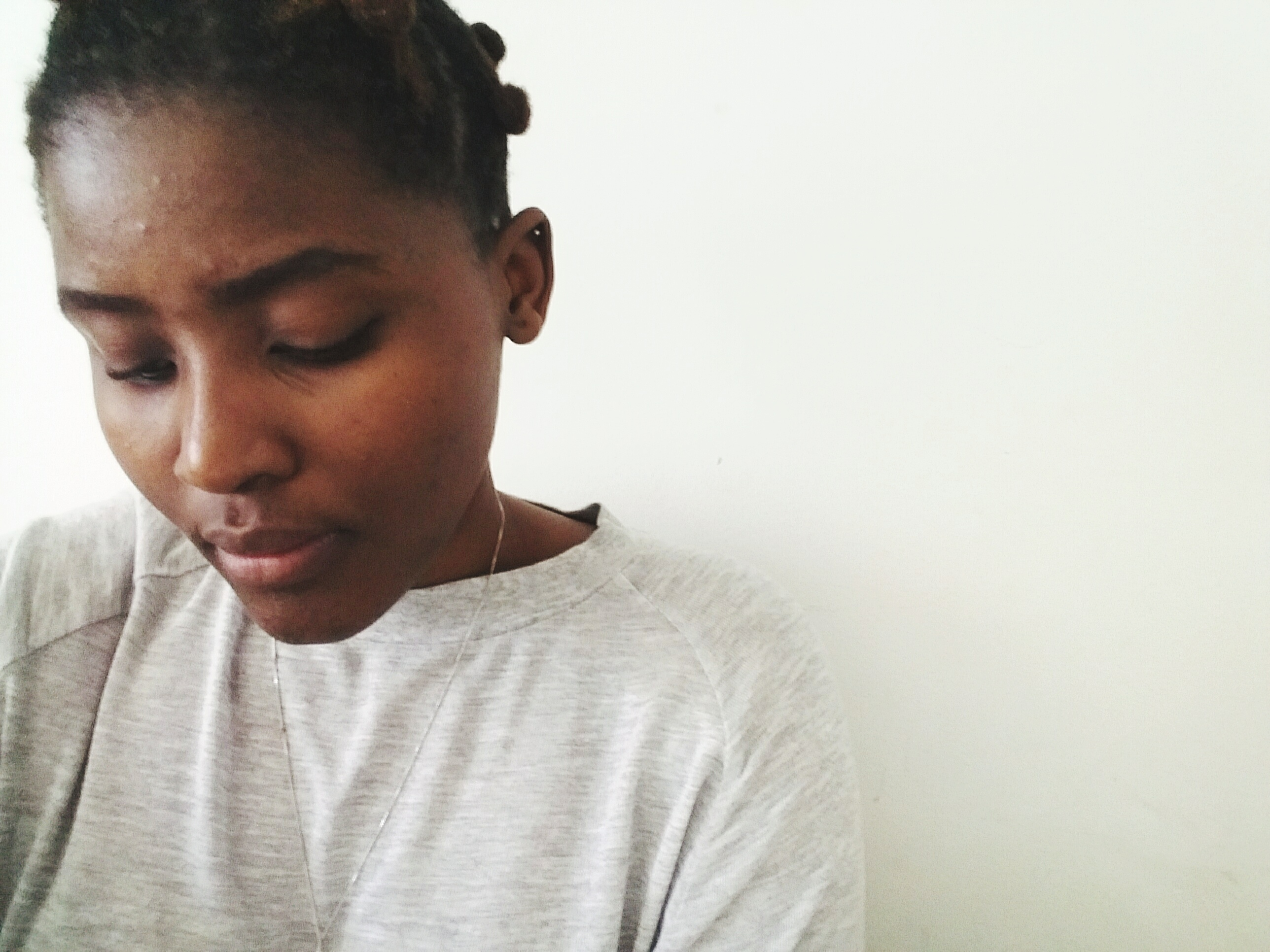 Thoughtful Woman Looking Down Against White Wall