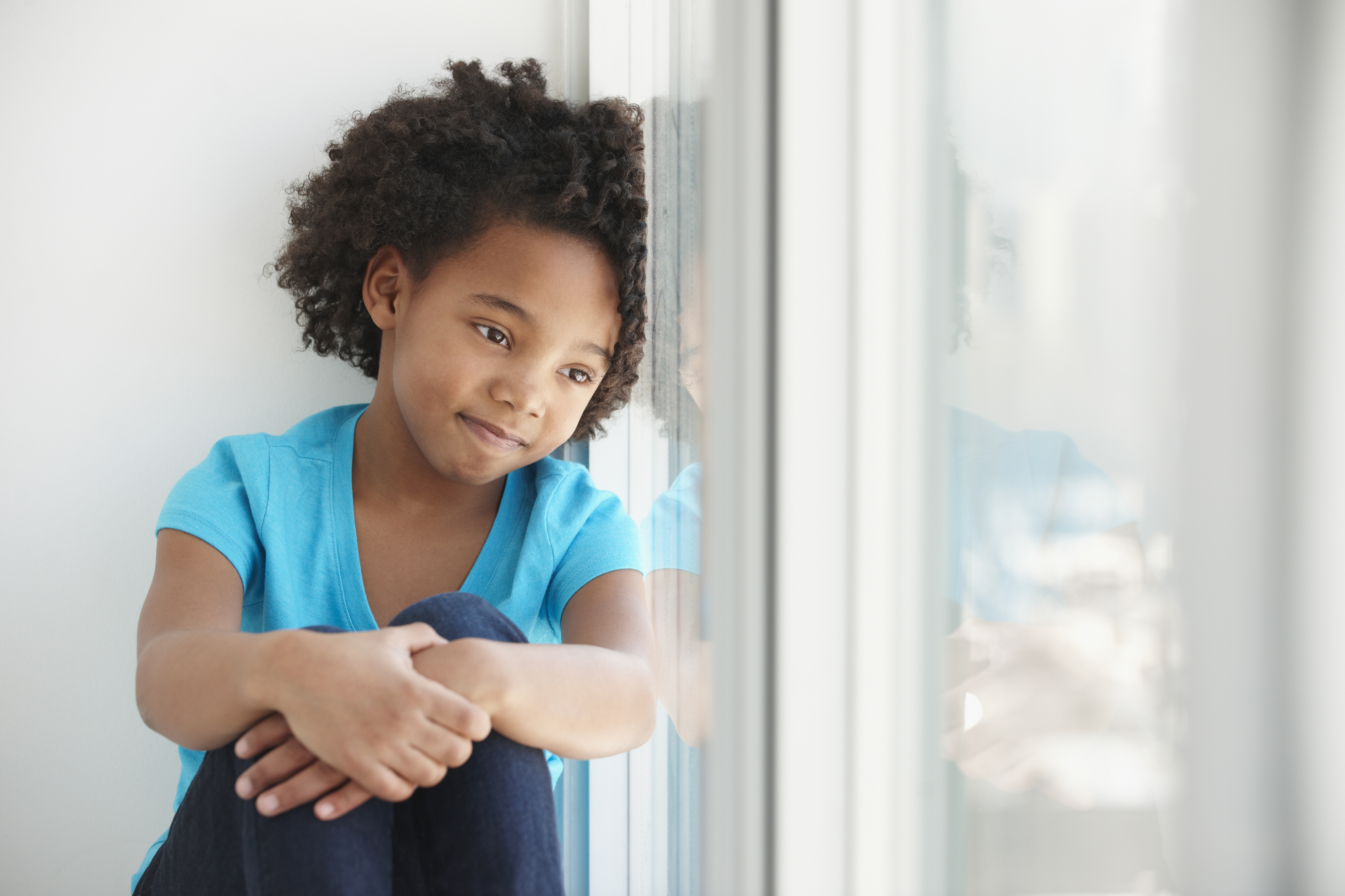 Black girl sitting in windowsill