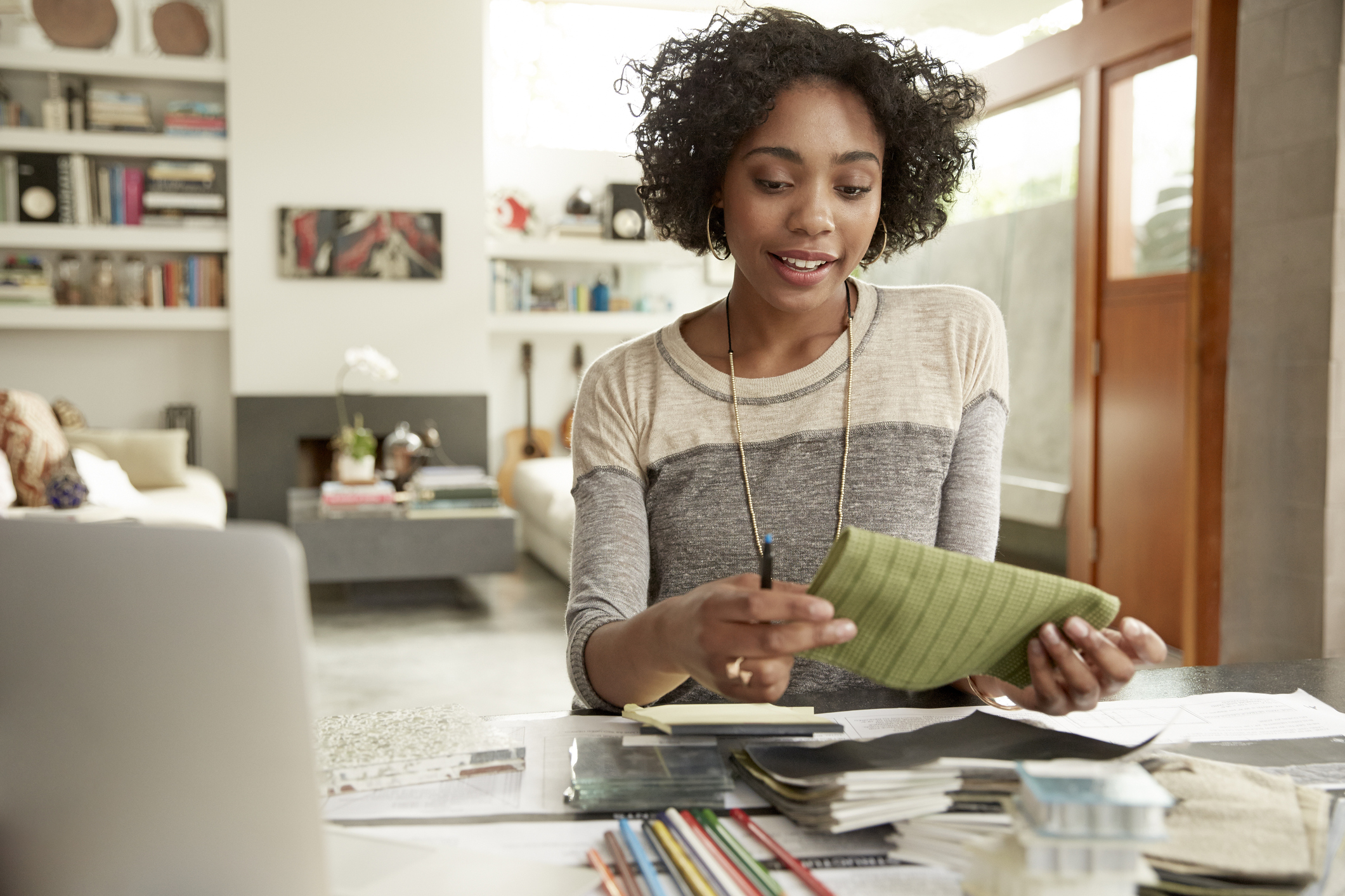 Female interior designer browsing fabric swatches at home office desk