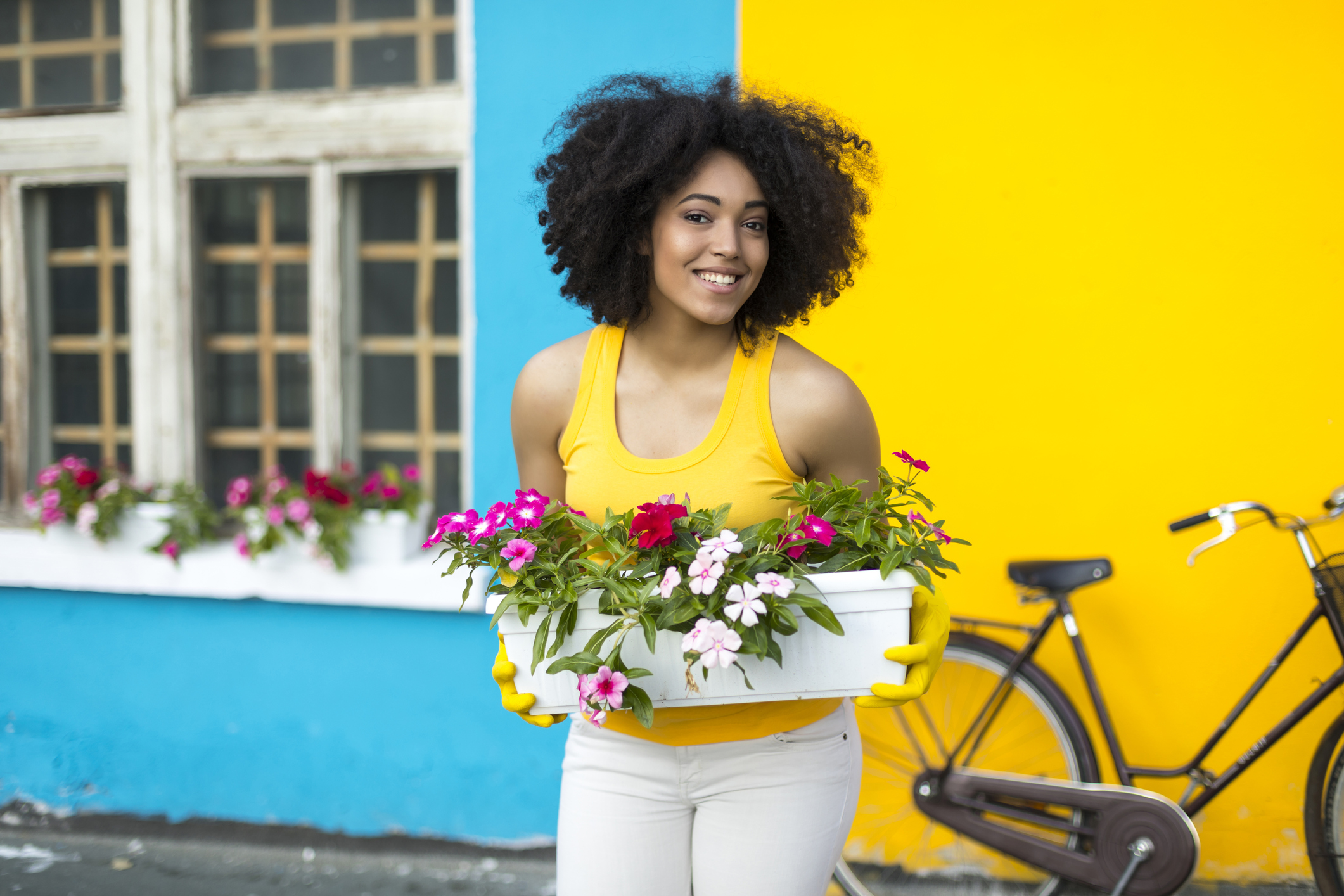 Smiling woman with bike carrying flowers in pot