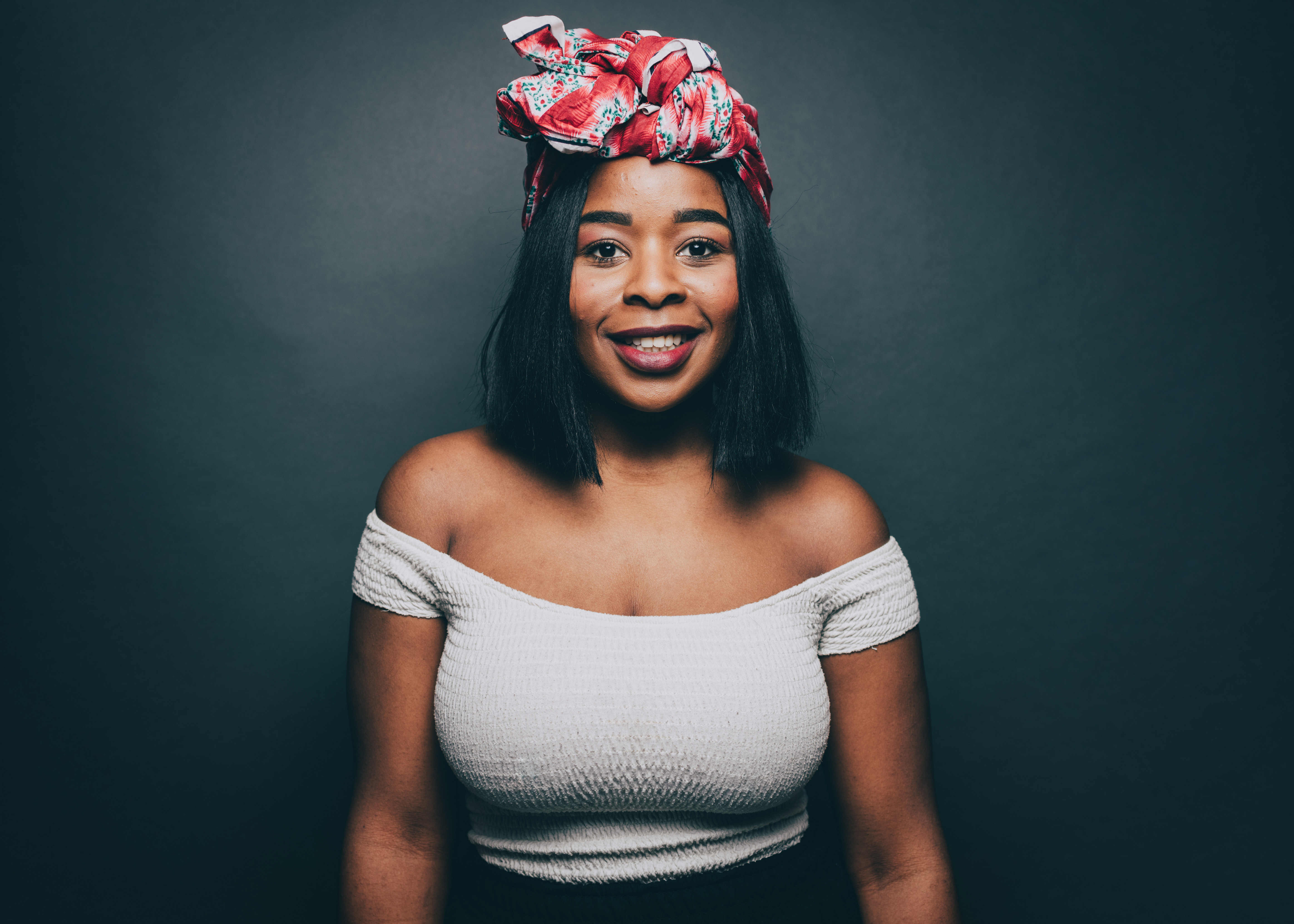Portrait of woman smiling while wearing head tie over gray background