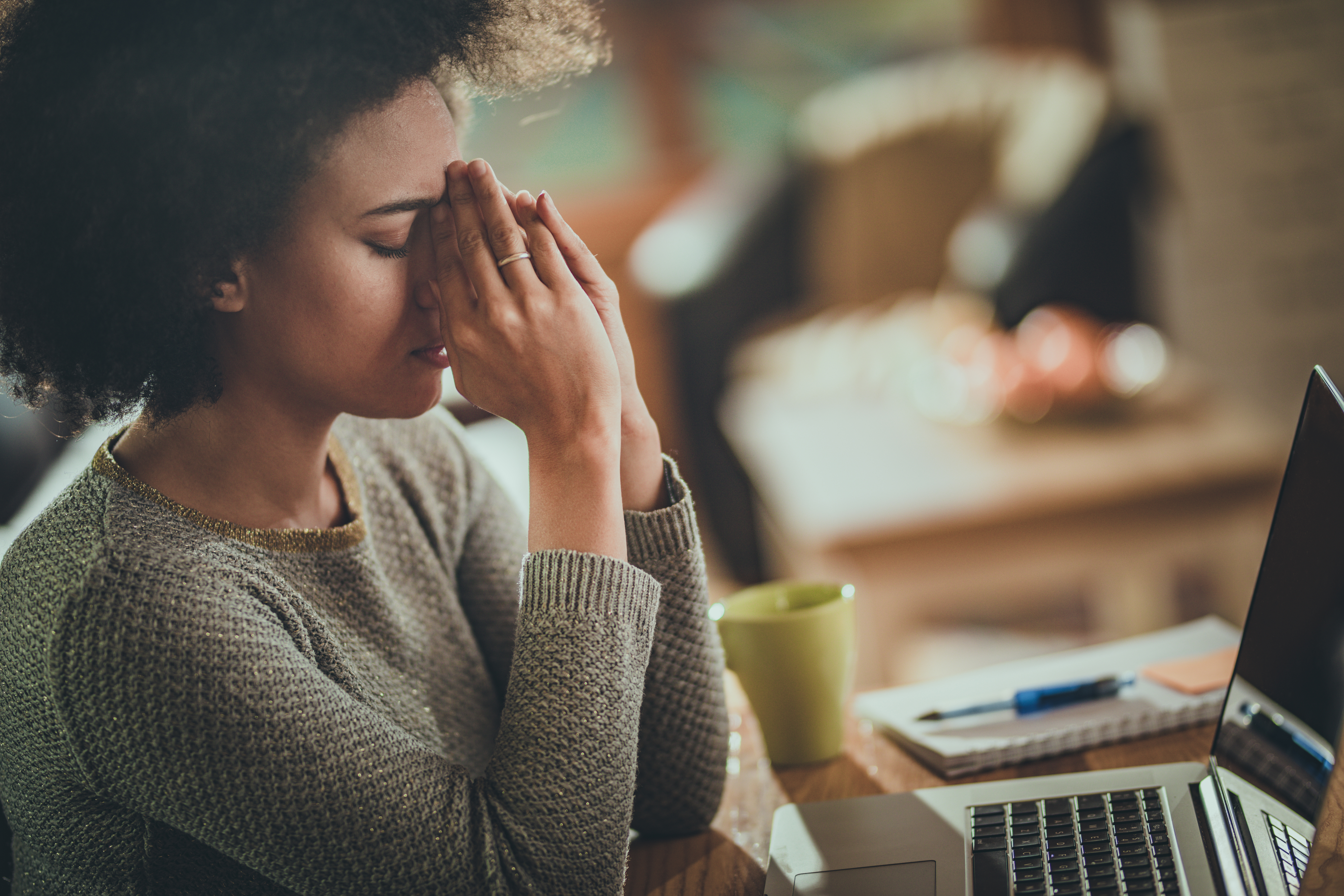 African American woman having a headache from working on computer.