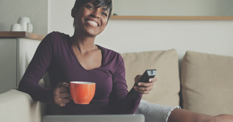 Beautiful black woman watching TV at home