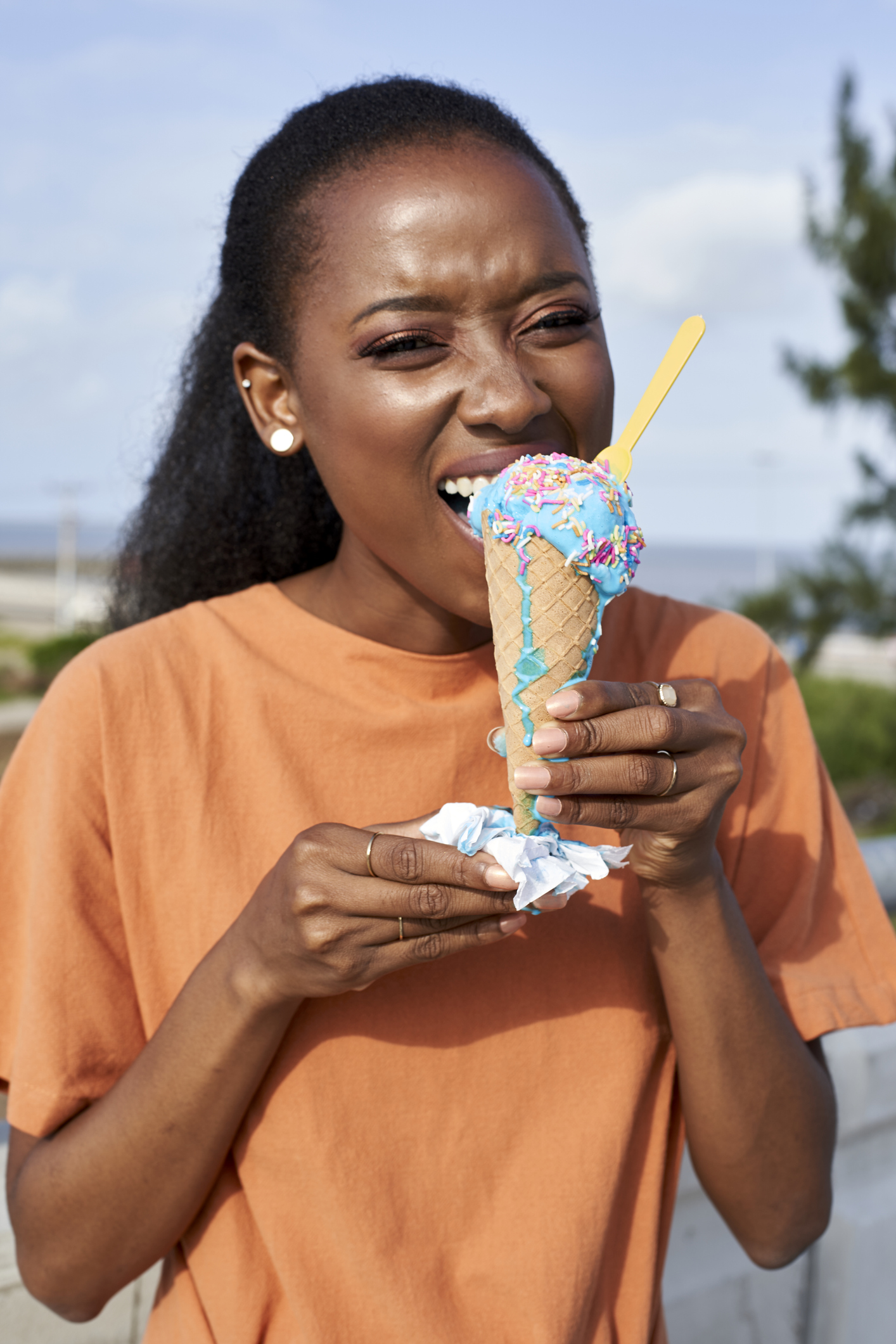 Portrait of young woman eating lightblue icecream outdoors