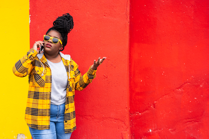 Afro woman on colorful background talking on a smartphone