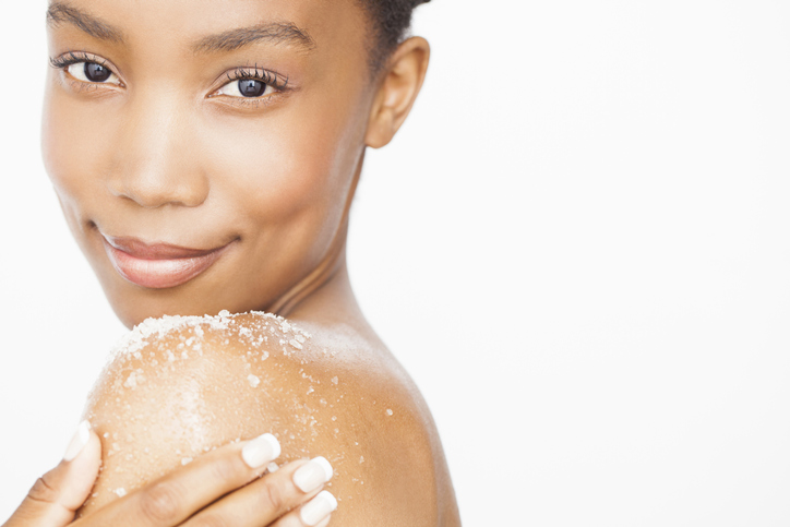 Woman exfoliating bare shoulder