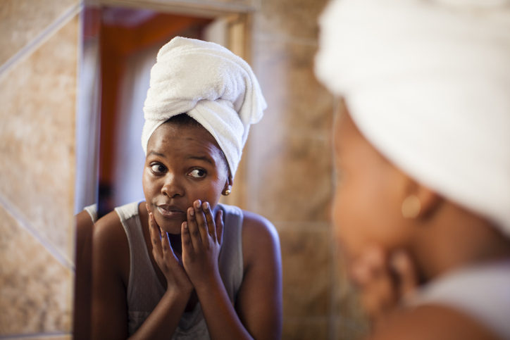 Young woman checking her skin in the mirror. Cape Town, Western Cape Province, South Africa