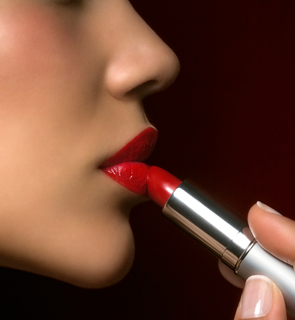 Young woman applying lipstick, close-up