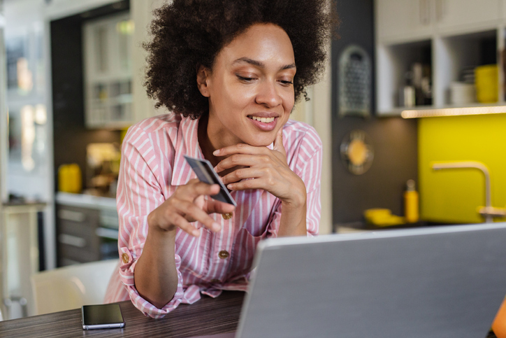 African American woman is shopping online with credit card in the kitchen