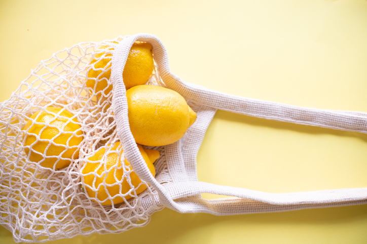 Yellow lemons in an eco-friendly grid on a yellow paper background. Conscious consumption, an alternative to plastic and bags. Reusable. Trendy yellow.