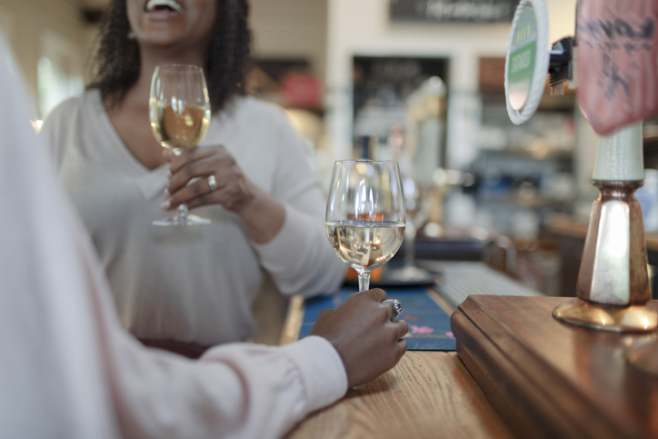 Women enjoying white wine at counter in pub