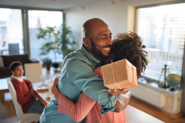 Cheerful African American father getting present by her daughter, celebrating.