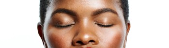 Beauty, makeup and confident black woman applying red lipstick against a white background. Closeup of a beautiful African American female face enjoying self care during grooming and skincare routine