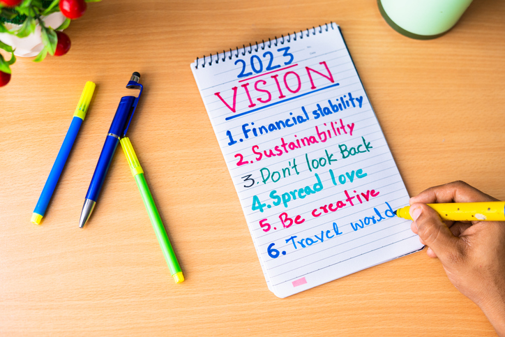 close up of hands adding making note of new year 2023 resolutions on dairy - concept of personal improvement or development and aspiration