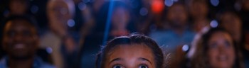 Mid-shot of young girl watching a film inside movie theater