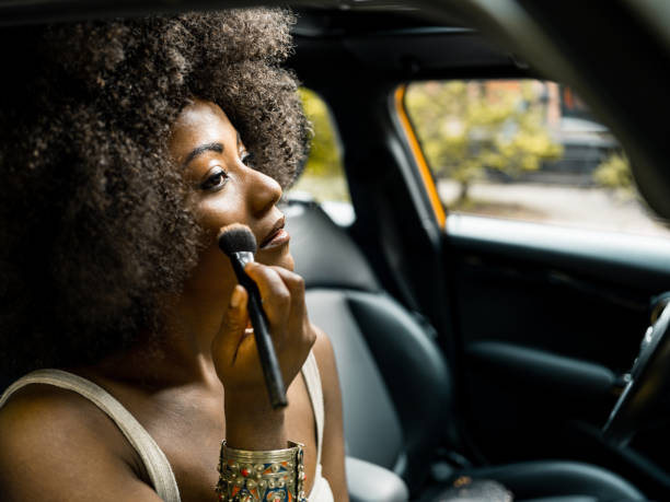 Black woman doing makeup in car