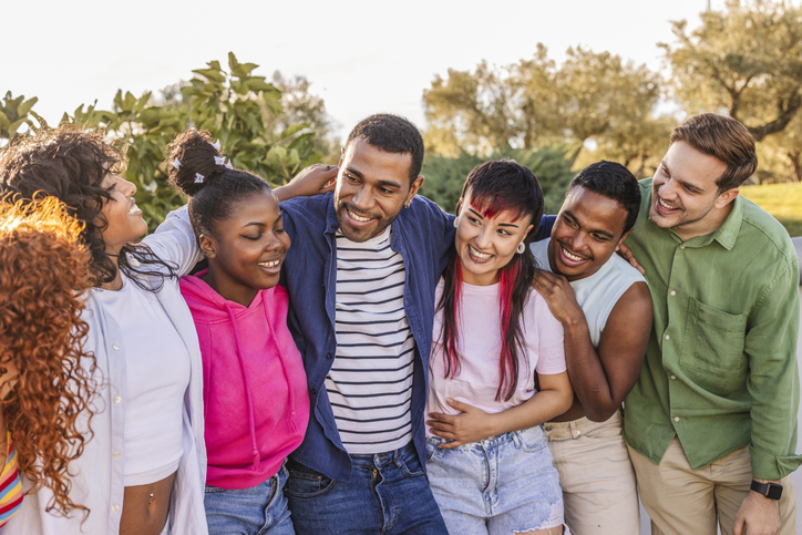 Diverse smiling young adults embracing outdoors together